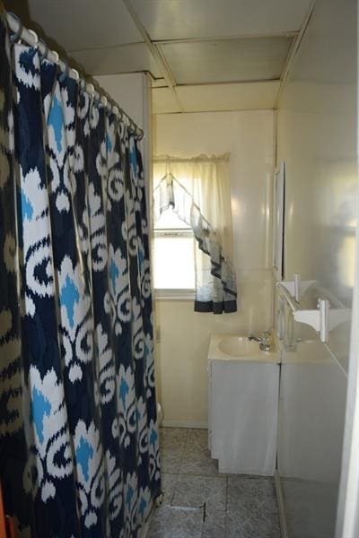 bathroom featuring vanity, tile floors, and a drop ceiling