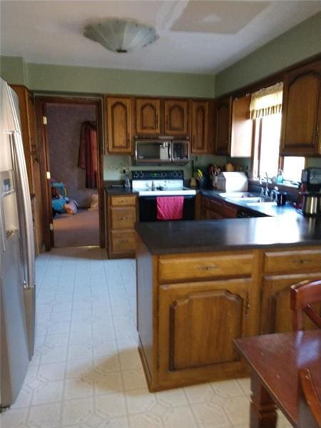 kitchen with kitchen peninsula, light tile floors, appliances with stainless steel finishes, and sink