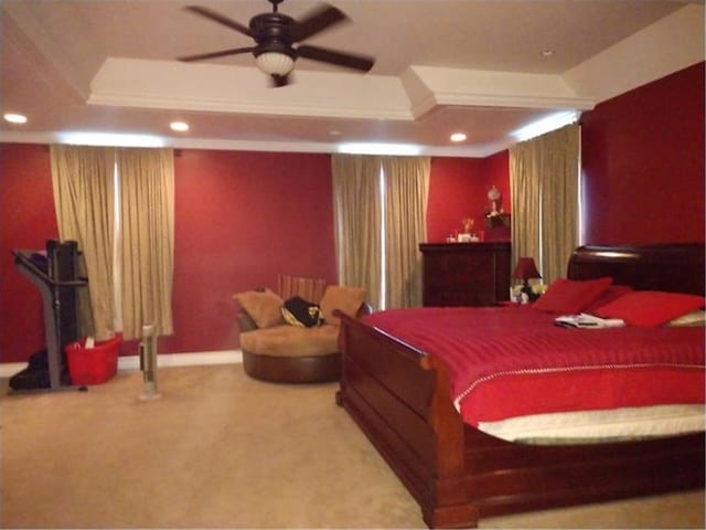 carpeted bedroom featuring a tray ceiling and ceiling fan