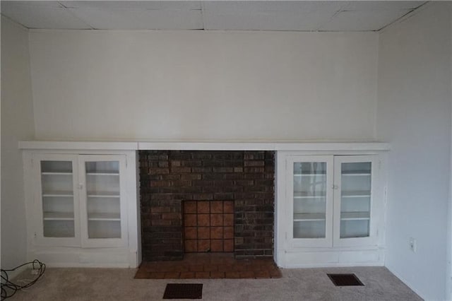 unfurnished living room featuring carpet and a brick fireplace