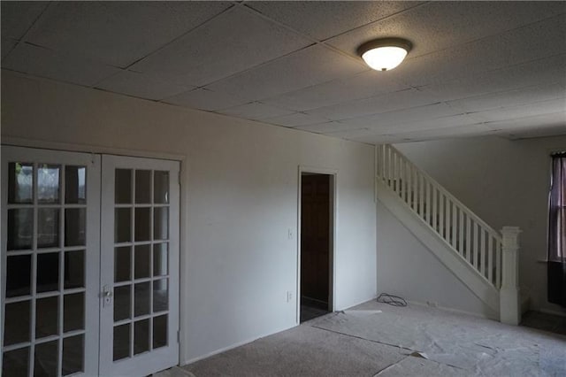 interior space with carpet floors, french doors, and a drop ceiling