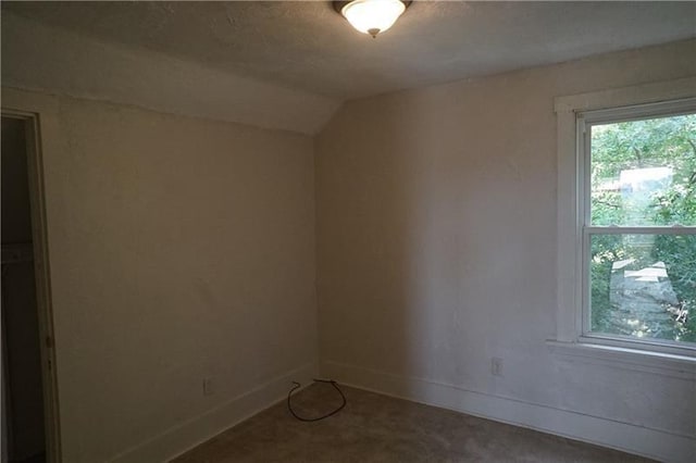 carpeted spare room with lofted ceiling