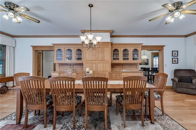 dining area with ornamental molding, ceiling fan with notable chandelier, and light hardwood / wood-style flooring