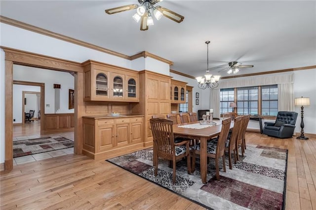 dining space featuring light wood-type flooring, ornamental molding, and ceiling fan with notable chandelier