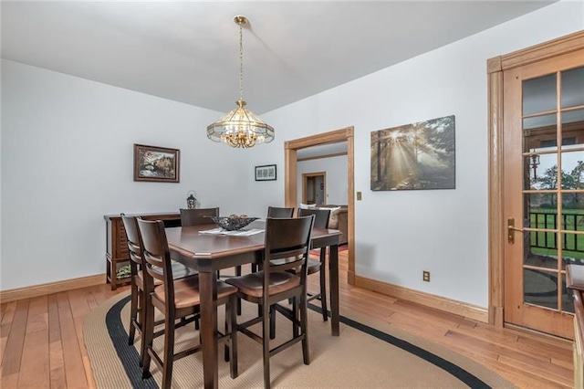 dining space with a notable chandelier and light hardwood / wood-style floors