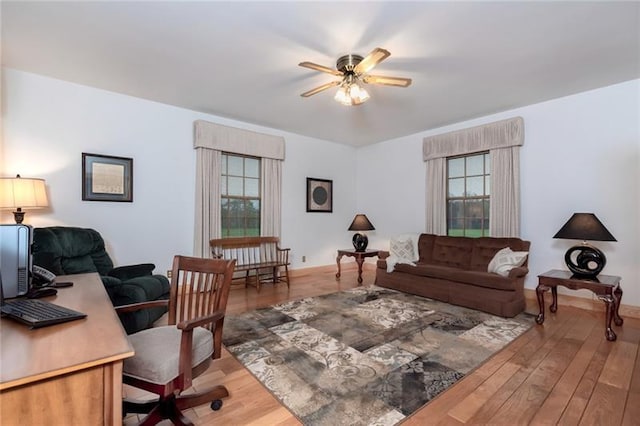 home office with light hardwood / wood-style floors and ceiling fan