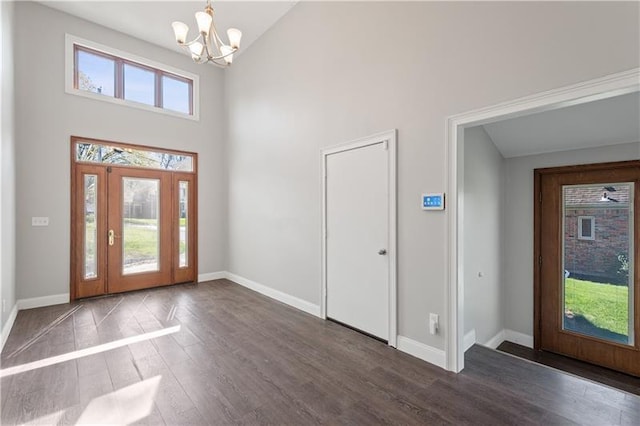 foyer featuring high vaulted ceiling, a chandelier, dark wood-type flooring, and a wealth of natural light