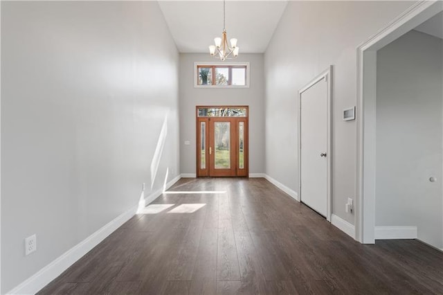 foyer featuring an inviting chandelier, dark wood-type flooring, and a towering ceiling