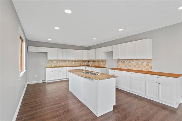 kitchen featuring white cabinets, backsplash, a kitchen island with sink, dark hardwood / wood-style floors, and sink