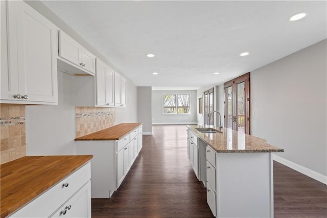 kitchen featuring sink, backsplash, dark hardwood / wood-style floors, and a center island with sink