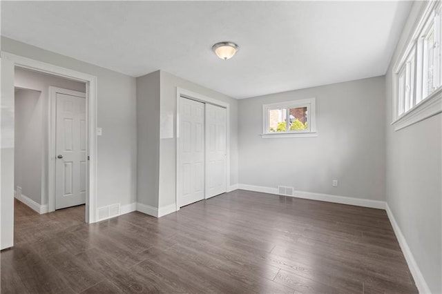 unfurnished bedroom with dark hardwood / wood-style flooring and a closet