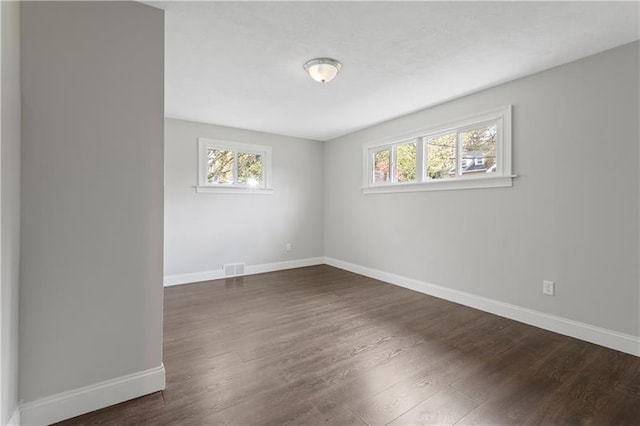 unfurnished room with dark wood-type flooring and a wealth of natural light