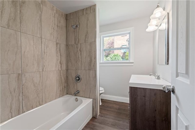 full bathroom with tiled shower / bath combo, vanity, hardwood / wood-style floors, and toilet