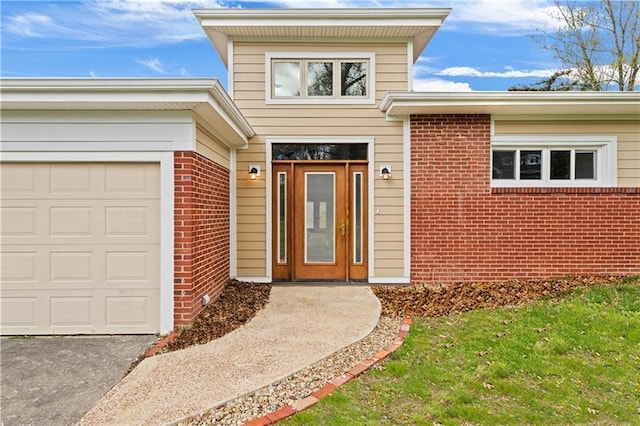 entrance to property featuring a lawn and a garage