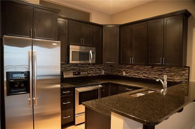 kitchen with stainless steel appliances, dark stone counters, kitchen peninsula, tasteful backsplash, and sink