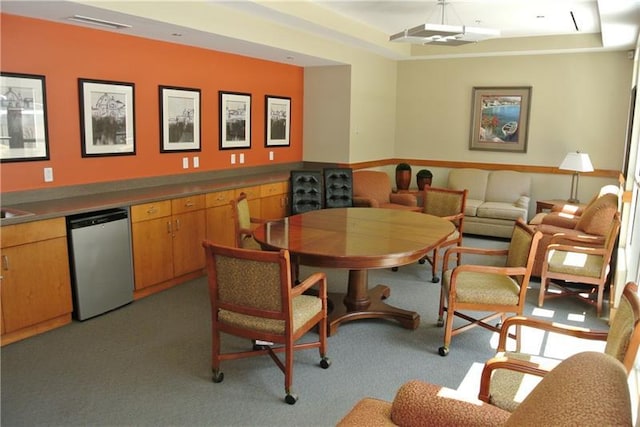 carpeted dining room with a raised ceiling