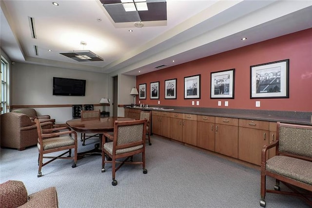 carpeted dining room with a tray ceiling