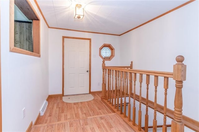 entryway with ornamental molding and light hardwood / wood-style floors