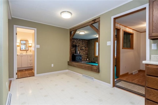 interior space featuring light tile floors, ornamental molding, and a wood stove