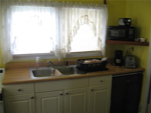 kitchen featuring wood counters, white cabinetry, sink, and a wealth of natural light