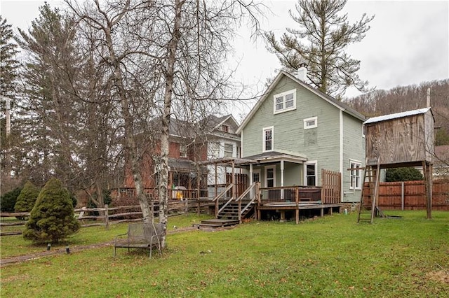 rear view of house featuring a lawn and a wooden deck