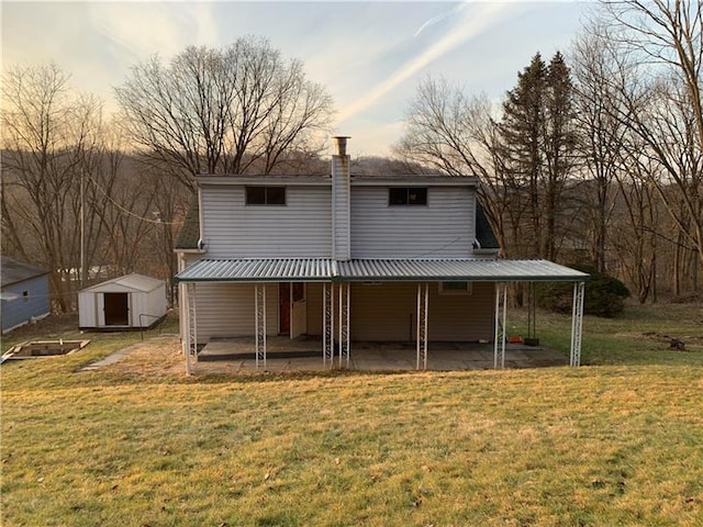 back of property with a yard, a patio area, and a shed