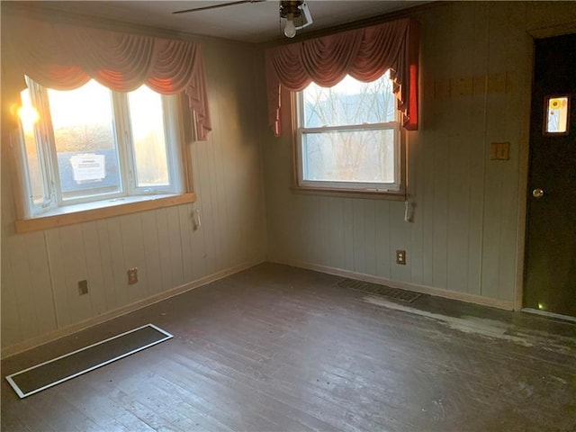 spare room with ceiling fan, dark wood-type flooring, and wood walls