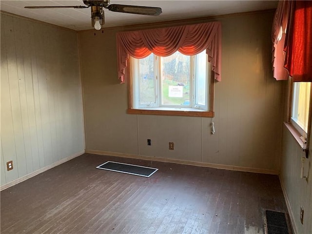 empty room with ceiling fan, plenty of natural light, and dark wood-type flooring