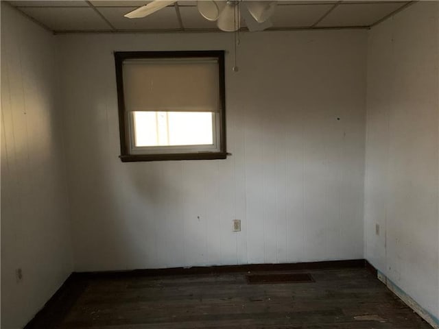 empty room with a paneled ceiling, ceiling fan, and dark hardwood / wood-style floors