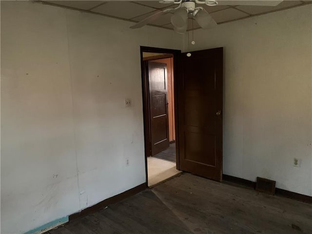 unfurnished room featuring ceiling fan, a paneled ceiling, and dark wood-type flooring