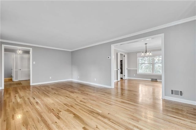 empty room featuring ornamental molding, a chandelier, and light wood-type flooring