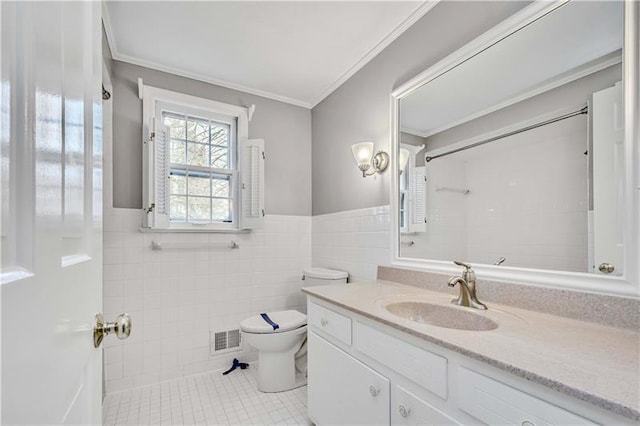 bathroom with tile walls, tile floors, vanity with extensive cabinet space, toilet, and ornamental molding