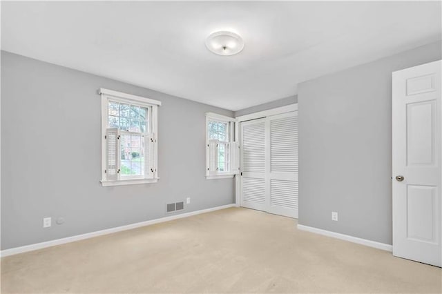 unfurnished bedroom featuring light carpet and a closet