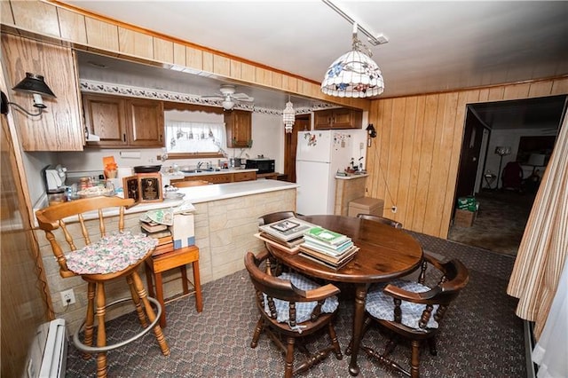 dining room featuring dark carpet, rail lighting, ceiling fan, and a baseboard heating unit