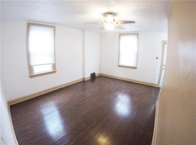 spare room featuring ceiling fan, a textured ceiling, dark hardwood / wood-style floors, and a healthy amount of sunlight