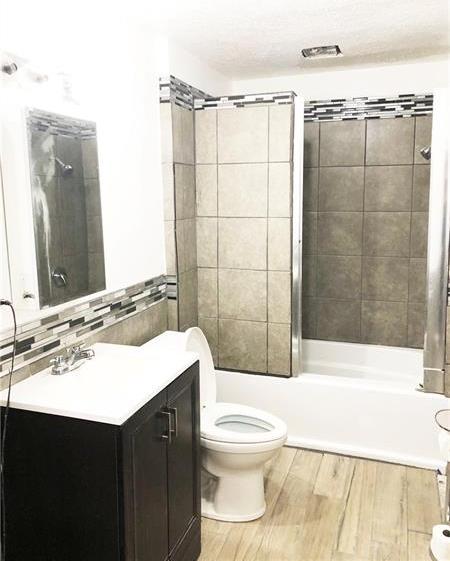 full bathroom featuring toilet, vanity, hardwood / wood-style flooring, and tiled shower / bath