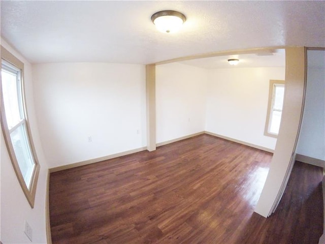 spare room featuring a textured ceiling and dark wood-type flooring