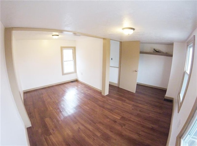 spare room with a wealth of natural light and dark hardwood / wood-style flooring