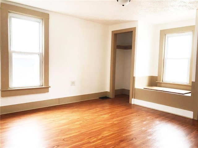 unfurnished bedroom with a textured ceiling, light hardwood / wood-style floors, and multiple windows