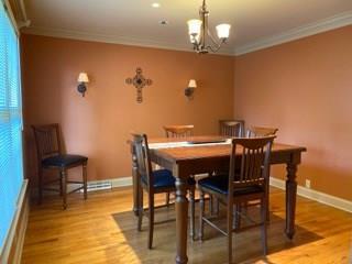 dining room with crown molding, light hardwood / wood-style flooring, and a chandelier