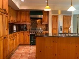 kitchen with decorative light fixtures, backsplash, stainless steel range, light tile floors, and wall chimney exhaust hood