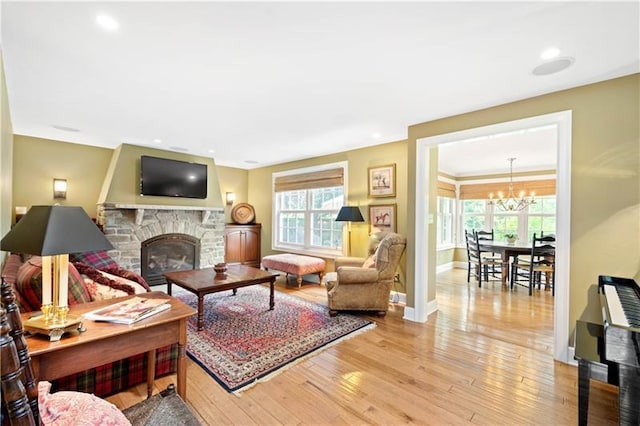 living room featuring a notable chandelier, a fireplace, light hardwood / wood-style flooring, and a wealth of natural light