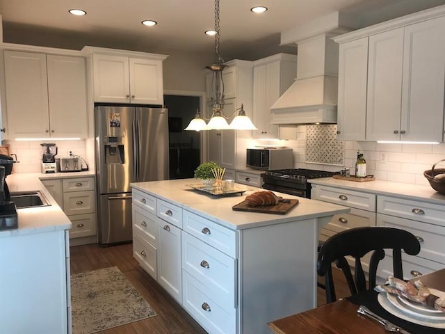 kitchen with custom range hood, a kitchen island, stainless steel appliances, backsplash, and white cabinets