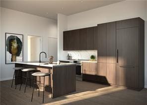 kitchen with a kitchen bar, a kitchen island with sink, dark wood-type flooring, and sink