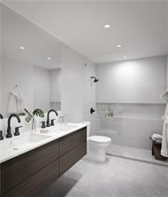 bathroom with tile floors, double vanity, and toilet