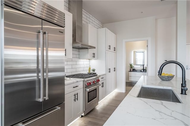 kitchen featuring light stone countertops, backsplash, light hardwood / wood-style floors, white cabinets, and high quality appliances