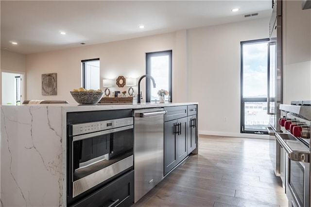 kitchen featuring stainless steel appliances, plenty of natural light, and dark wood-type flooring