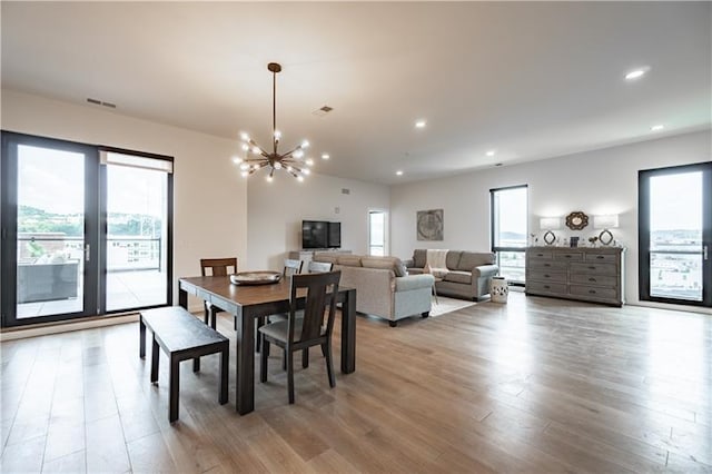 dining area featuring a wealth of natural light, a chandelier, and light wood-type flooring