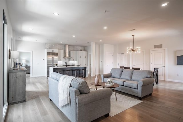 living room with a chandelier, sink, and light hardwood / wood-style flooring