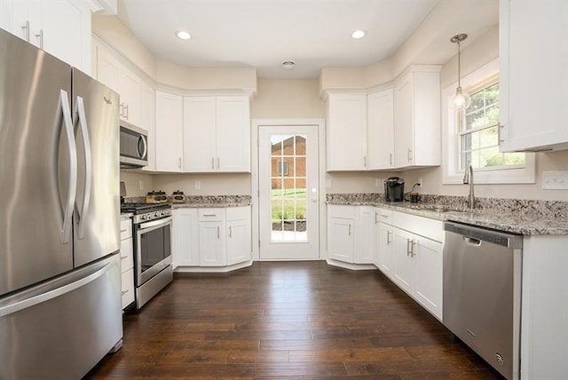 kitchen featuring light stone countertops, dark wood-type flooring, appliances with stainless steel finishes, white cabinetry, and hanging light fixtures